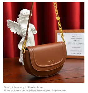 Détail d'un sac besace marron avec chaîne dorée sur une surface en bois vintage