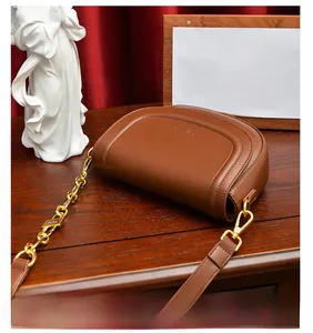 Détail d'un sac besace marron avec chaîne dorée et coutures raffinées sur fond en velours