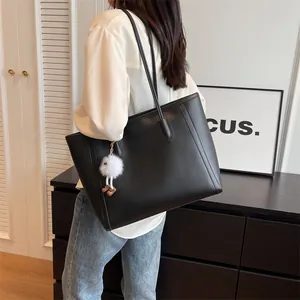Detailed view of black PU leather tote bag with a cute plush bear charm on shoulder strap