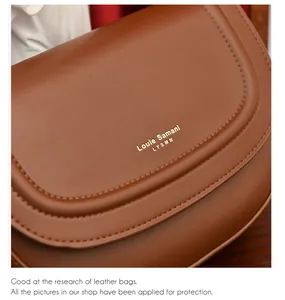 Détail du sac besace en cuir marron avec logo doré et surpiqûres décoratives