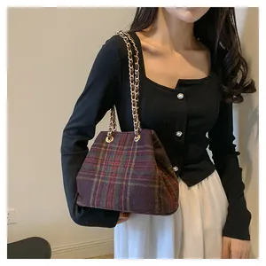 Close-up of vintage plaid bucket bag with gold chain strap on a stylish model
