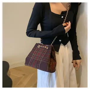 Detail of British style plaid bucket bag with gold chain strap and woolen texture