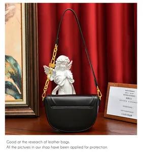 Détail du sac selle en cuir noir avec grosse chaîne dorée et pendentif cadenas