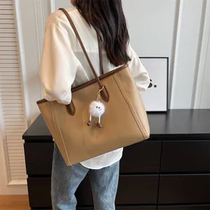 Detail of khaki PU leather tote bag featuring brown contrast handles and a plush charm