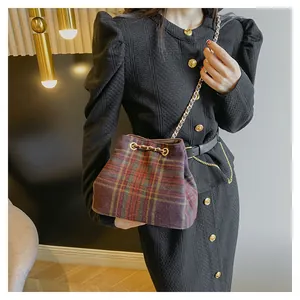 Close-up of retro plaid bucket bag with gold chain and wool tweed texture on a model