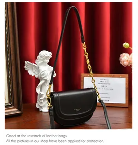 Détail du sac besace en cuir noir avec une chaîne dorée épaisse et une bandoulière en cuir