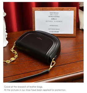 Détail du sac selle noir demi-lune avec chaîne dorée et fond en velours rouge élégant