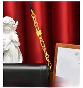 Détail du sac en cuir noir brillant avec chaîne dorée épaisse et boucle de cadenas dorée