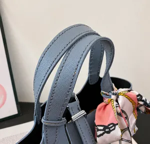 Detail of blue litchi pattern bucket bag featuring dual handles and a silk scarf accent