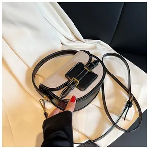 Detail of canvas saddle bag featuring black leather trim and gold buckle accents