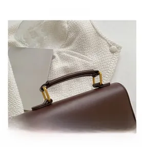 Close-up of vintage brown leather handbag featuring round top handle and gold hardware