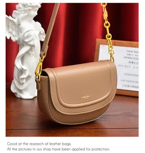 Détail du sac besace en cuir marron avec lettrage doré et bandoulière chaîne épaisse