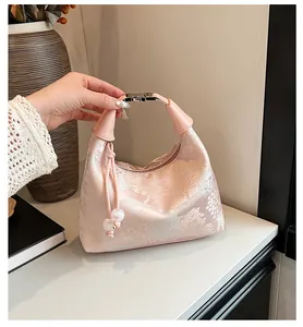 Close-up of pink velvet cloud bag with floral jacquard pattern and beaded tassel