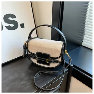 Classic beige canvas saddle bag with black leather trim and elegant gold hardware