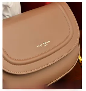 Gros plan d'un sac besace en cuir marron avec logo doré et coutures de haute qualité
