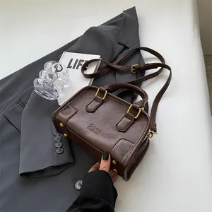 Vintage dark brown Boston handbag with pebbled texture and dual handles over a grey blazer