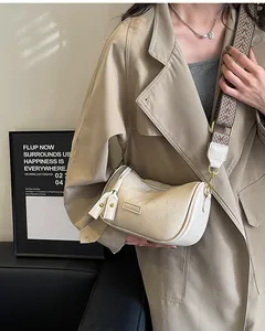 Detail of cream pleated crossbody bag with patterned wide strap and metallic logo plate