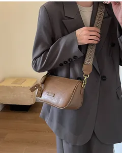 Close-up of brown textured leather crossbody bag with woven geometric shoulder strap