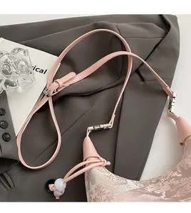 Close-up of pink beaded handbag with silver floral embroidery and adjustable leather strap