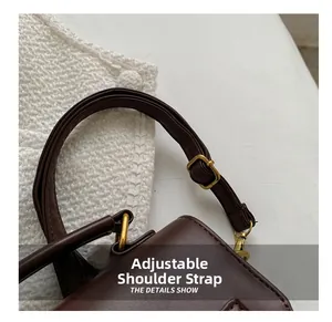 Close-up of the adjustable dark brown leather shoulder strap with gold metal buckle
