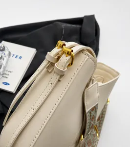 Close-up of cream leather bucket bag with gold hardware and geometric woven strap