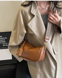 Detail of vintage brown crossbody bag with wide geometric woven strap and BOJIEDS logo
