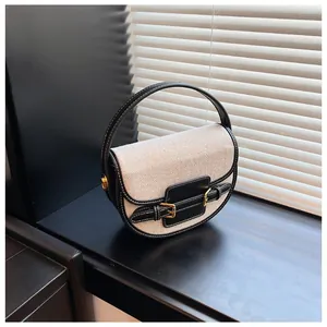 Detail view of canvas saddle bag with black leather trim and white contrast stitching