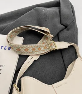 Detail of adjustable geometric jacquard strap and polished metal buckle on off-white bag