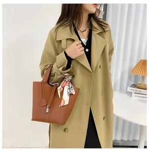 Detailansicht einer braunen Bucket-Bag aus Leder mit Seidenschal am Tragegriff