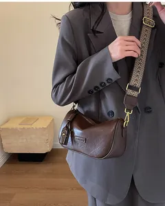 Detailed view of dark brown leather crossbody bag with ethnic woven wide shoulder strap
