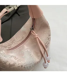 Detail of pink jacquard fabric bag showing smooth metal zipper and beaded drawstring pull