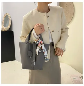 Detail der grauen Bucket Bag aus Litchi-Leder mit Metallschloss und gebundenem Seidenschal