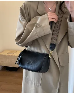 Detailed view of black leather crossbody bag with vintage wide wave pattern strap