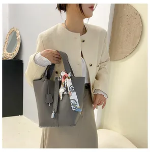 Detail der dunkelgrauen Beuteltasche mit Lychee-Struktur, Vorhängeschloss und bedrucktem Seidenschal
