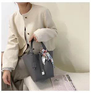 Detail der grauen Beuteltasche aus genarbtem Leder mit Schloss und buntem Seidenschal