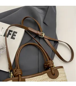 Détail de la bandoulière en cuir réglable sur sac seau en paille avec nœud de corde