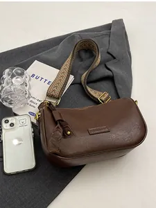Detailed view of brown vintage shoulder bag next to iPhone for size comparison