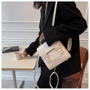 Chic cream white vintage satchel with gold hardware worn by model in black suit jacket