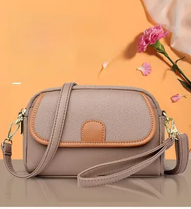 Close-up of litchi pattern leather texture and gold zipper on a chic crossbody phone bag