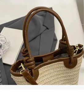 Détail d'un sac seau en paille tressée avec anses en cuir marron et boucles dorées