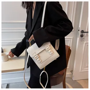 Detail of cream leather crossbody bag with buckle straps and logo on a chic lifestyle setting