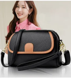 Crossbody bag detail showing black litchi grain leather with brown trim and gold hardware