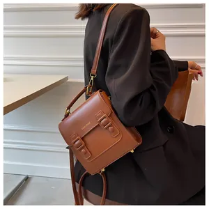 Close-up of vintage brown satchel bag with double buckle straps and hand strap detail