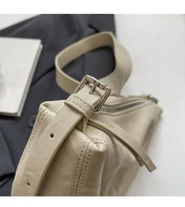 Detail van verstelbare schouderband en zilveren metalen gesp op beige litchi lederen tas