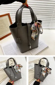Detailed view of greyish brown bucket bag with lychee texture and silk scarf handle