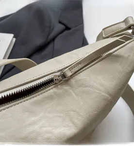 Detail van een gladde metalen rits en leertextuur op een beige crossbody tas dames
