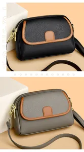 Detail of dual-zipper crossbody bags in black and gray with litchi grain texture