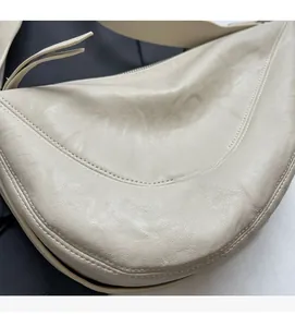 Close-up van crèmewitte crossbodytas met zachte textuur en fijn stikwerk detail