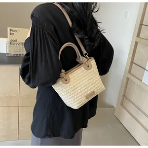 Détail du sac seau en paille contrasté avec tissage crème et bordure en cuir kaki