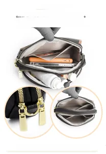 Close-up of black leather bag with three zip compartments and gold hardware detail